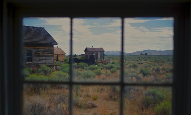 Window overlooking field and abandoned buildings